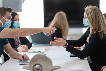 Image showing new normal businesspeople on meeting using antibacterial hand sanitizer