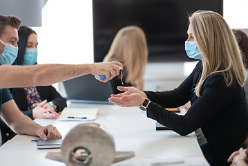 Image showing new normal businesspeople on meeting using antibacterial hand sanitizer