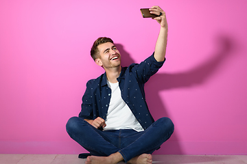 Image showing man sitting on the floor of the house and using the phone