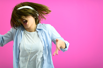 Image showing brunette lady in black glasses dancing and listening music isolate on pink background