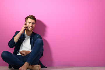 Image showing man sitting on the floor of the house and using the phone