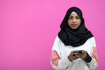 Image showing afro woman uses a cell phone in front of a pink background