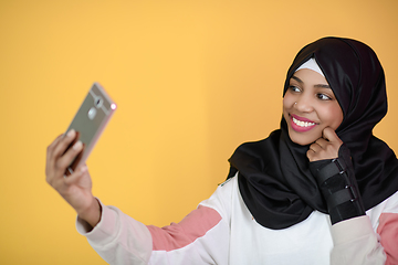 Image showing african muslim woman with a beautiful smile takes a selfie with a cell phone