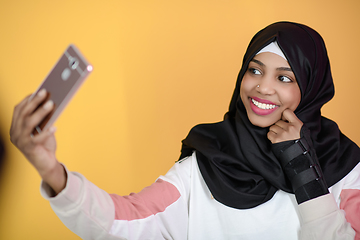 Image showing african muslim woman with a beautiful smile takes a selfie with a cell phone