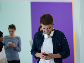 Image showing group of diverse teenagers use mobile devices while posing for studio photo