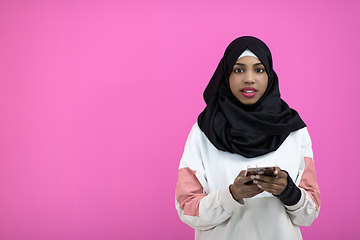 Image showing afro woman uses a cell phone in front of a pink background