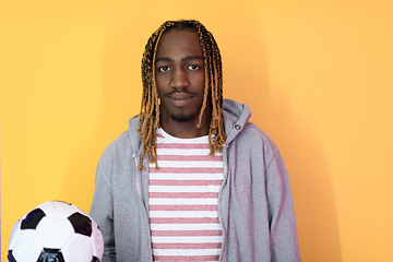 Image showing afro man posing on a yellow background while holding a soccer ball