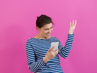 Image showing a surprised-faced girl looks at her cell phone as she stands in front of a pink background