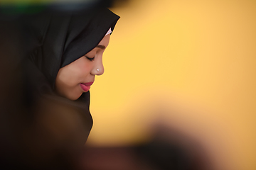 Image showing african muslim woman wearing hijab and traditional muslim clothes posing in front of green background