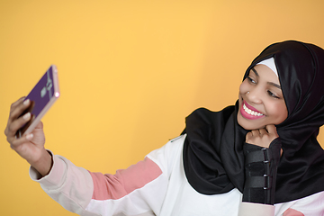 Image showing african muslim woman with a beautiful smile takes a selfie with a cell phone