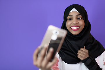 Image showing african muslim woman with a beautiful smile takes a selfie with a cell phone