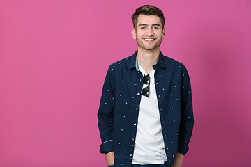 Image showing a portrait of a young man wearing a blue shirt and posing in front of a pink background 