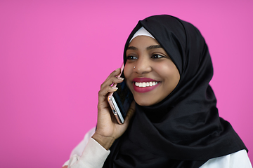 Image showing afro woman uses a cell phone in front of a pink background