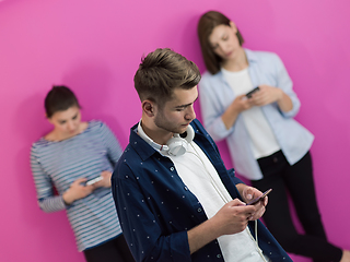 Image showing group of diverse teenagers use mobile devices while posing for studio photo