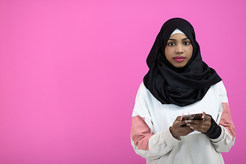 Image showing afro woman uses a cell phone in front of a pink background