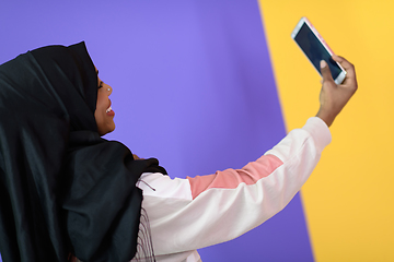 Image showing african muslim woman with a beautiful smile takes a selfie with a cell phone