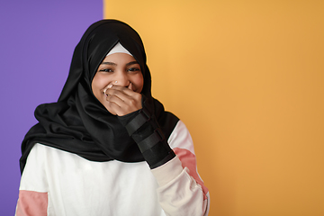 Image showing African Muslim woman wearing hijab and traditional Muslim clothes posing in front of yellow background