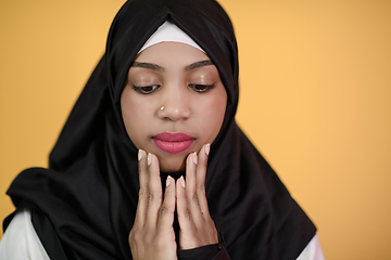 Image showing african muslim woman wearing hijab and traditional muslim clothes posing in front of green background