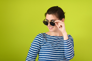 Image showing woman in sunglasses posing in front of a green background