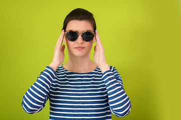 Image showing woman in sunglasses posing in front of a green background