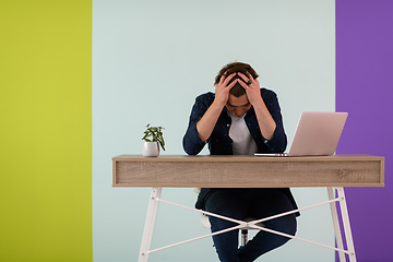 Image showing disappointed and annoyed man sitting at a table and looking at a laptop