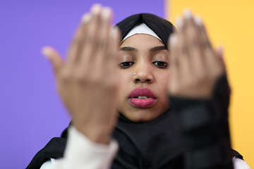 Image showing african muslim woman wearing hijab and traditional muslim clothes posing in front of green background