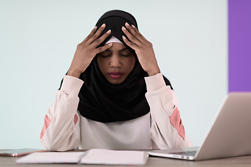 Image showing afro girl wearing a hijab is disappointed and sad sitting in her home office and using a laptop