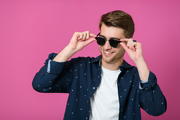 Image showing a portrait of a young man wearing a blue shirt and posing in front of a pink background 