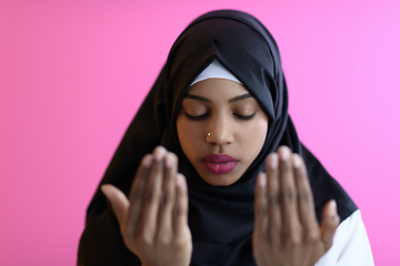 Image showing Modern African Muslim woman makes traditional prayer to God, keeps hands in praying gesture, wears traditional white clothes