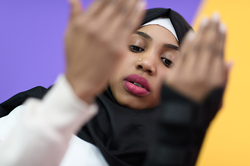 Image showing african muslim woman wearing hijab and traditional muslim clothes posing in front of green background