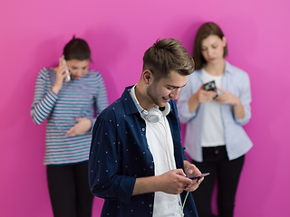 Image showing group of diverse teenagers use mobile devices while posing for studio photo