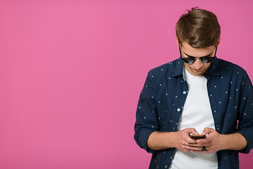 Image showing a young man wearing a blue shirt and sunglasses using a smartphone