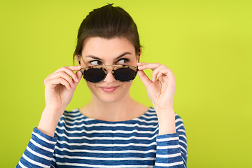 Image showing woman in sunglasses posing in front of a green background