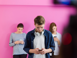 Image showing group of diverse teenagers use mobile devices while posing for studio photo