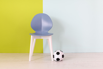 Image showing modern blue chair and soccer ball in front of a blue green background