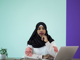 Image showing afro girl wearing a hijab is disappointed and sad sitting in her home office and using a laptop