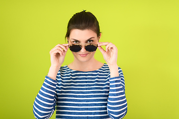 Image showing woman in sunglasses posing in front of a green background