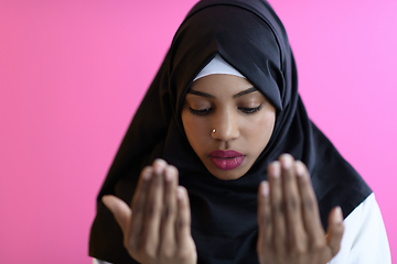 Image showing Modern African Muslim woman makes traditional prayer to God, keeps hands in praying gesture, wears traditional white clothes