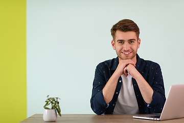 Image showing Smiling young man freelancer using laptop studying online working from home