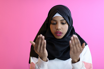 Image showing Modern African Muslim woman makes traditional prayer to God, keeps hands in praying gesture, wears traditional white clothes