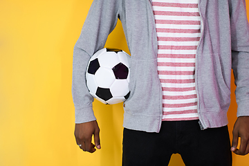 Image showing afro man posing on a yellow background while holding a soccer ball