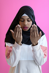 Image showing Modern African Muslim woman makes traditional prayer to God, keeps hands in praying gesture, wears traditional white clothes