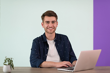 Image showing Smiling young man freelancer using laptop studying online working from home