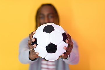 Image showing afro man posing on a yellow background while holding a soccer ball