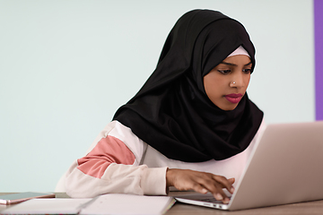 Image showing afro girl wearing a hijab is disappointed and sad sitting in her home office and using a laptop