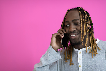 Image showing afro guy uses a phone while posing in front of a pink background.