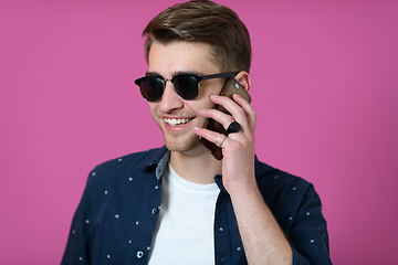 Image showing a young man wearing a blue shirt and sunglasses using a smartphone