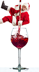 Image showing Happy Christmas Santa Claus climbing on trickle of wine on white background