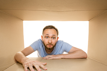 Image showing Young man opening the biggest postal package isolated on white