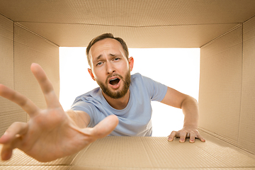 Image showing Young man opening the biggest postal package isolated on white